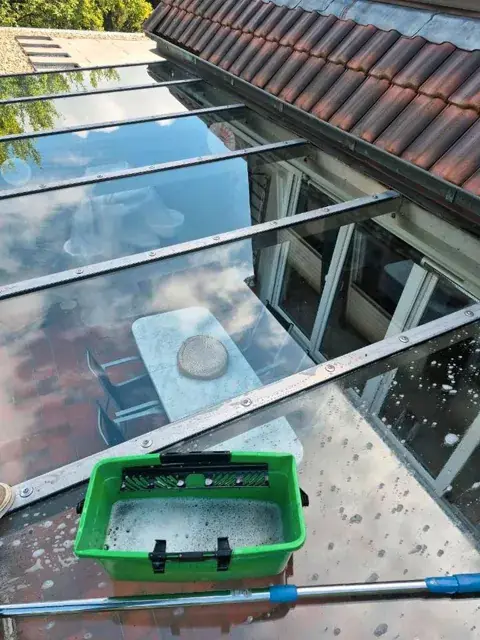Glasdach während der Reinigung mit Eimer und Teleskopstange